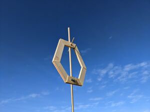 VLF Antenna (Approx 0.8m2, wood, copper wire, audio jack) hanging from a wooden pole against a blue sky.